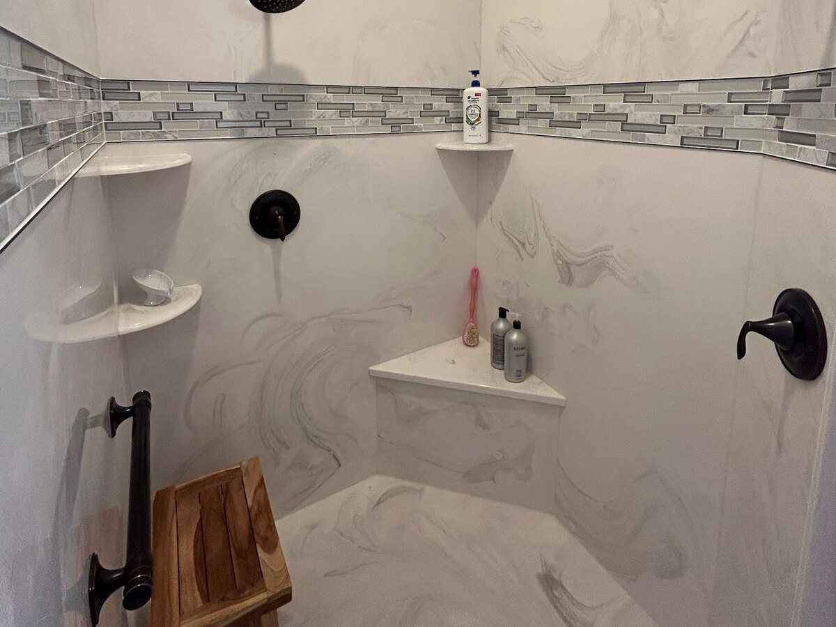 Accessible walk-in shower Walk-in shower with a grab bar, built-in corner seat and cultured marble walls