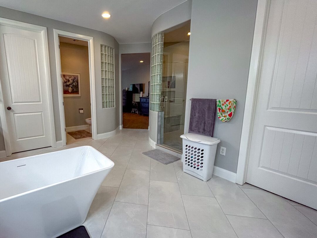 Master bathroom with a freestanding soaking tub and a glass block shower wall