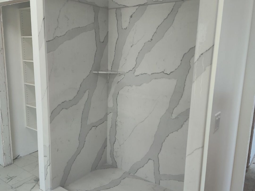 Tyvarian shower surround in a bold Calacatta pattern with a recessed shelf